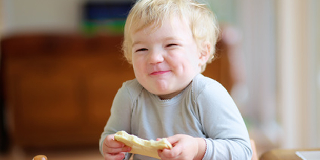 Cute toddler girl eating sandwich in the morning