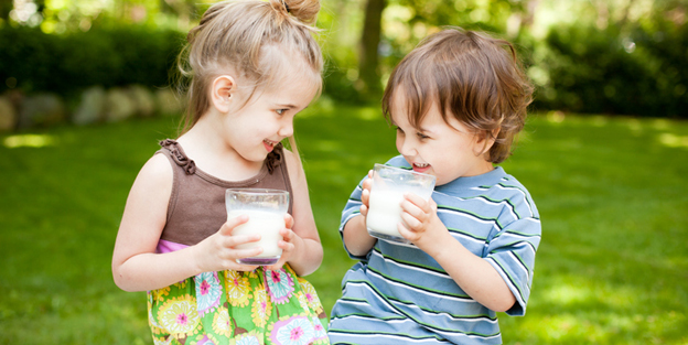 Two Little Kids Drinking Milk While Outdoors